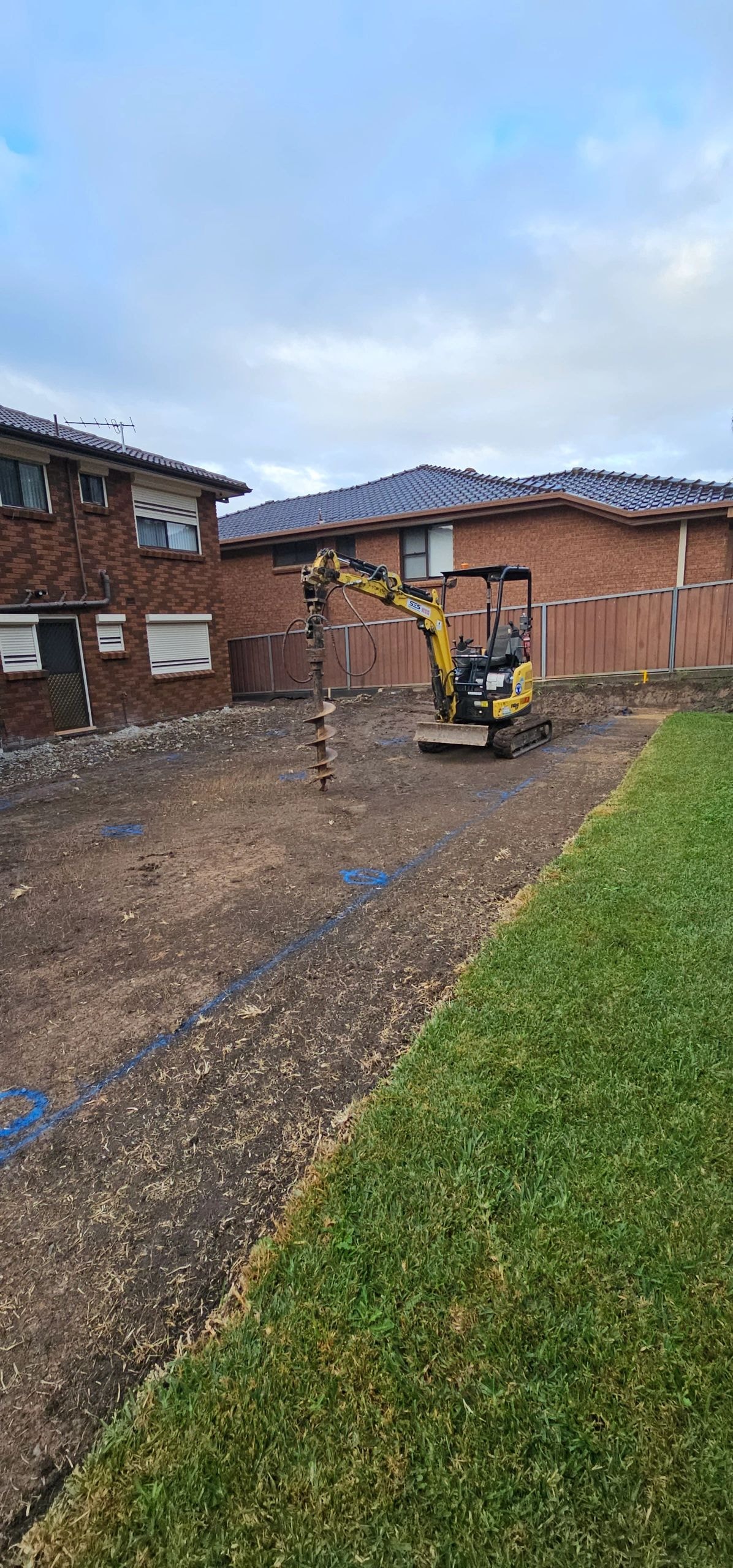 Excavator in backyard next to brick homes